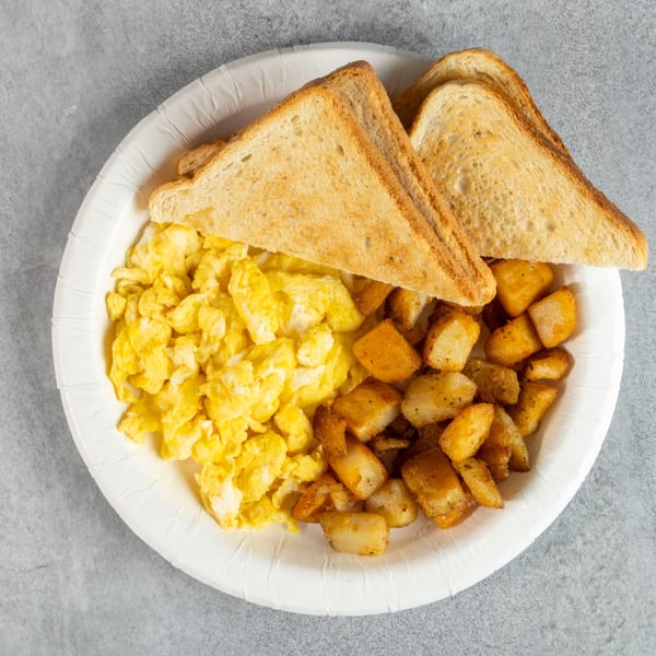 A breakfast plate with scrambled eggs, crispy home fries, and two slices of toast.
